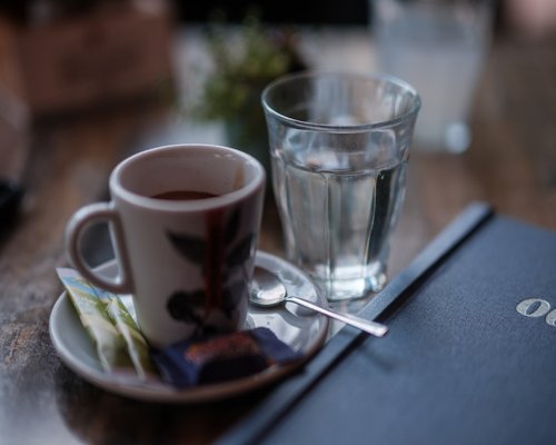 A warm mug of traditional Colombian black coffee placed beside a glass of fresh mineral water