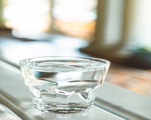 Clear clean glass of fresh water reflecting calm natural morning light