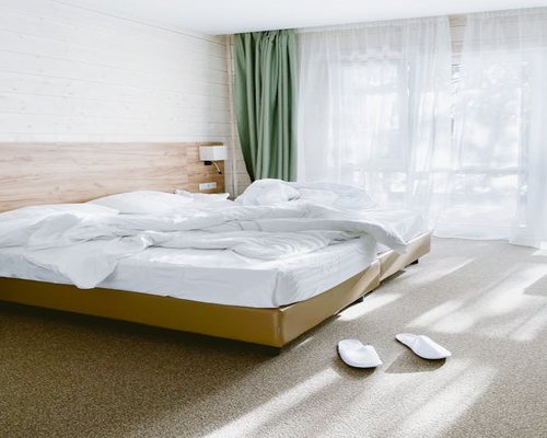 Cozy tidy bedroom with window view and soft clean linen prepared for rest
